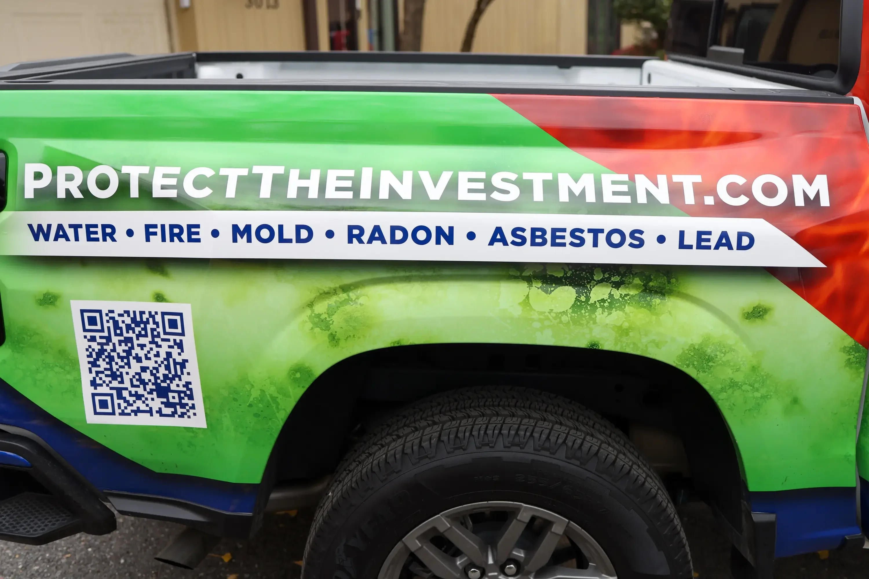 Green and red vehicle wrap with company branding and service list on truck bed