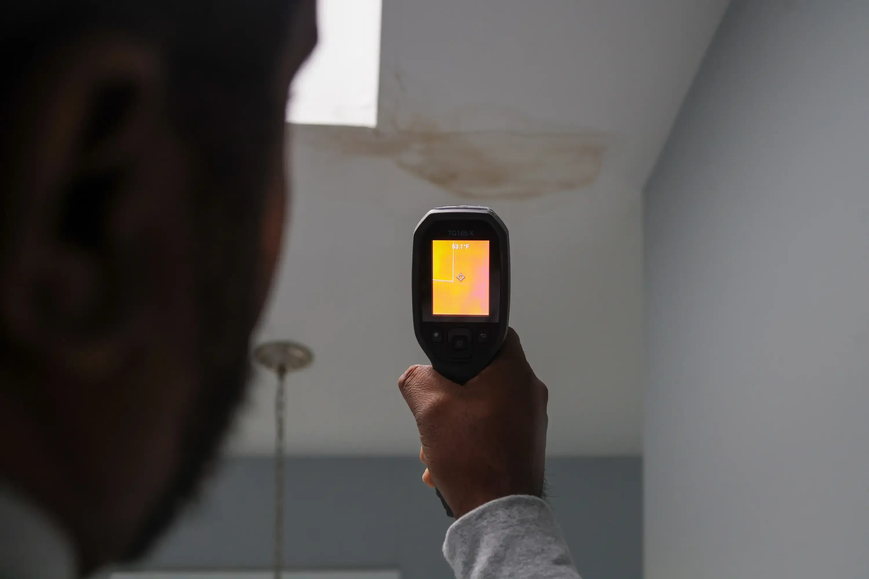 Thermal imaging camera displaying heat signature scan of interior wall and ceiling moisture patterns