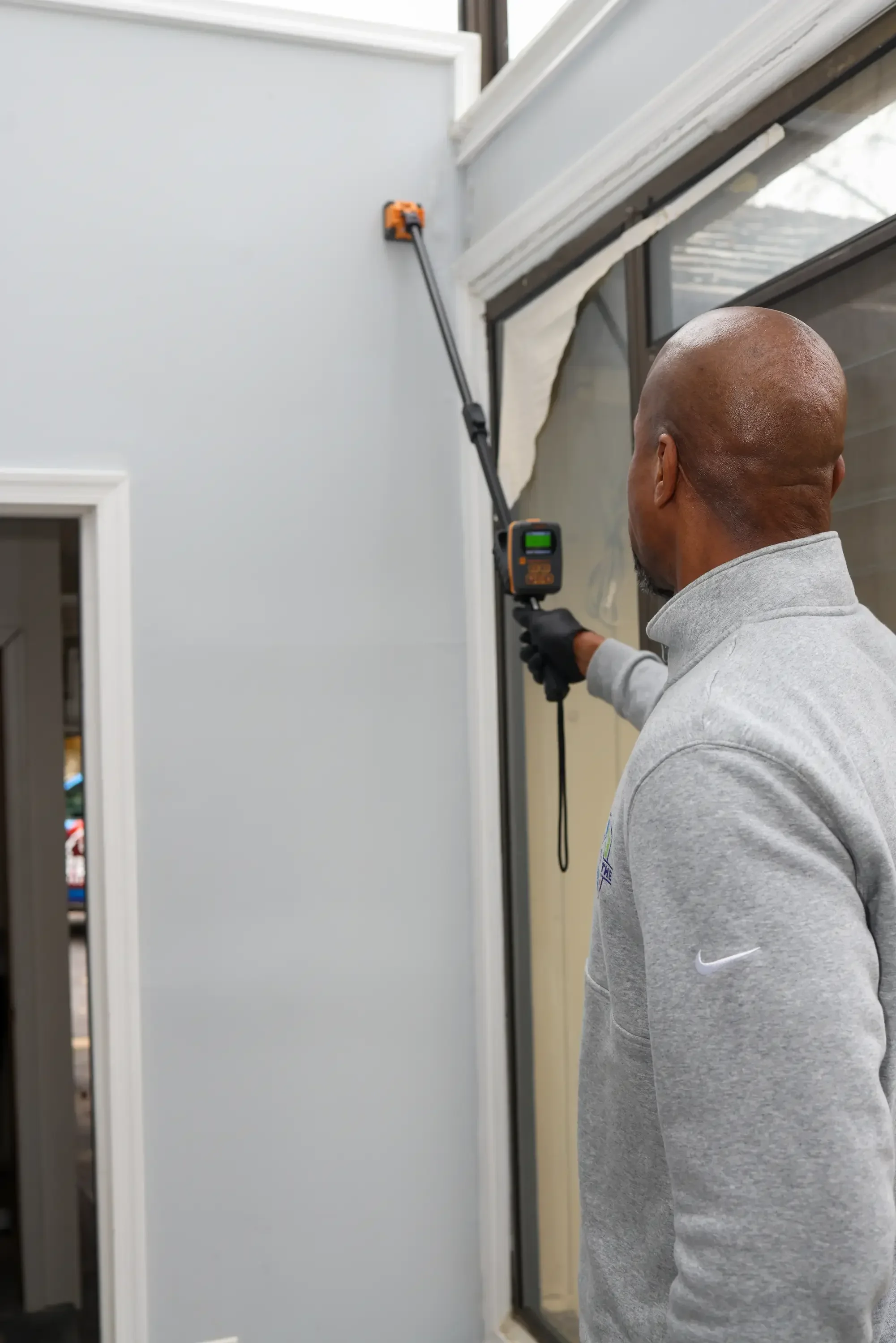 Inspector using digital moisture meter to test wall moisture levels during home inspection