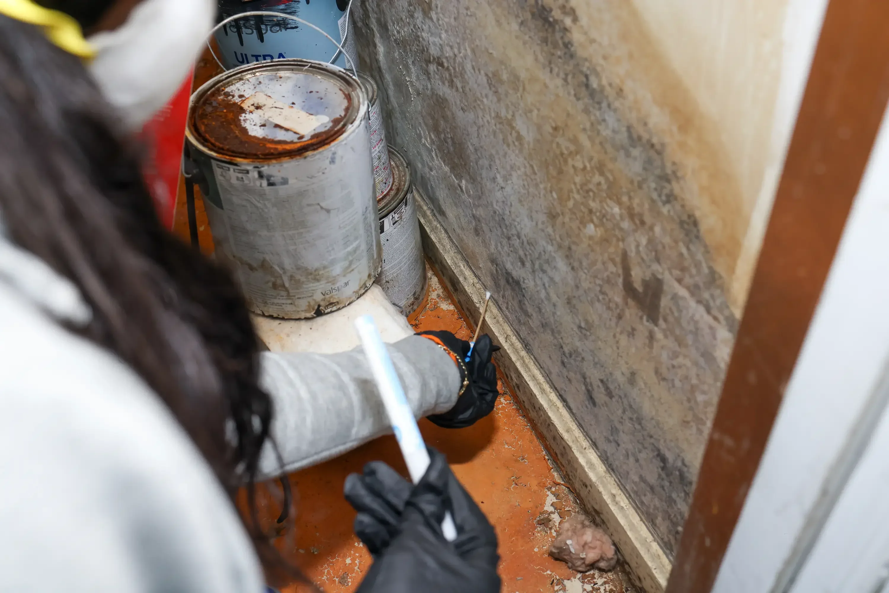 Inspector collecting mold sample from concrete foundation wall using sterile equipment