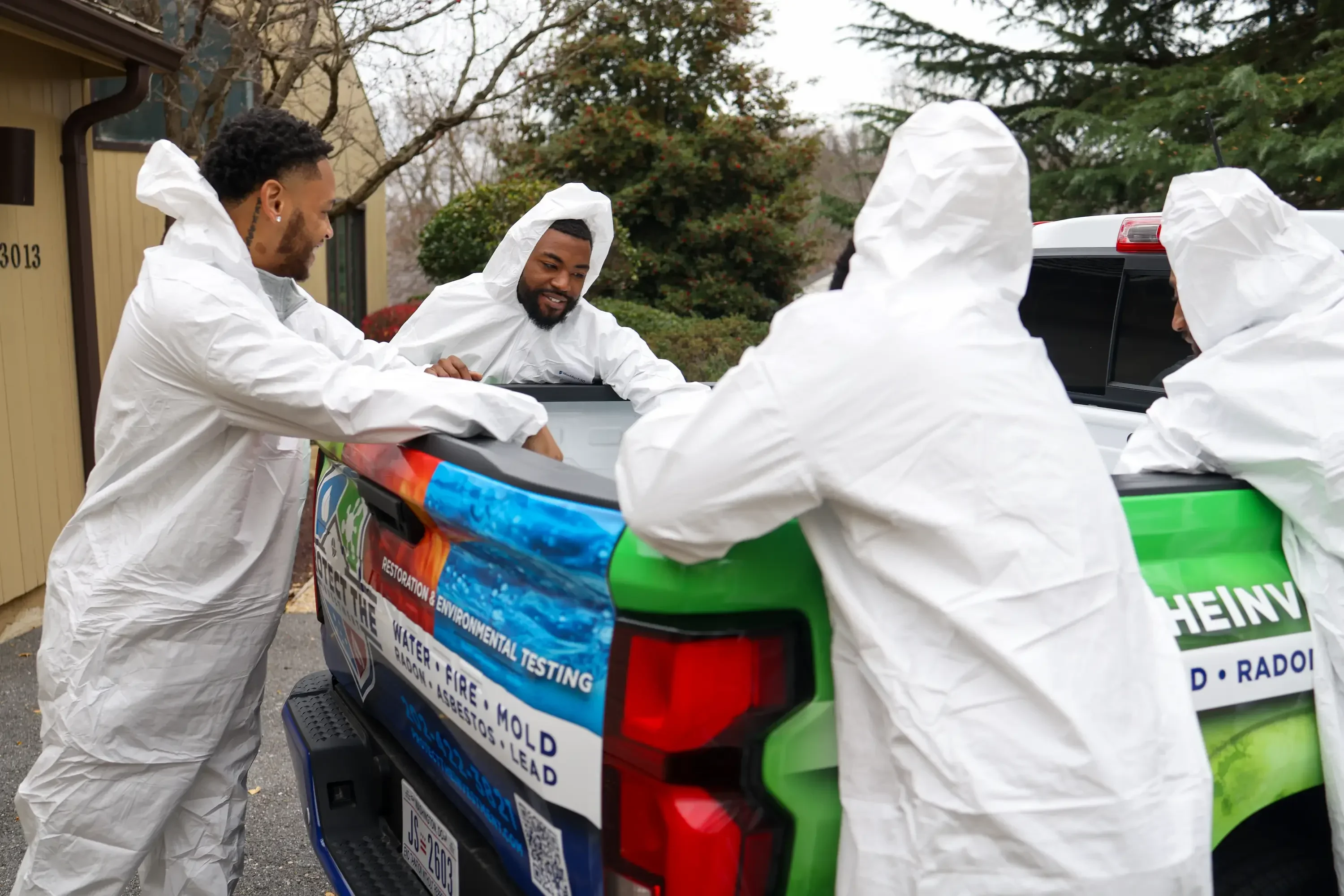 Team members in protective gear conducting environmental testing on residential property